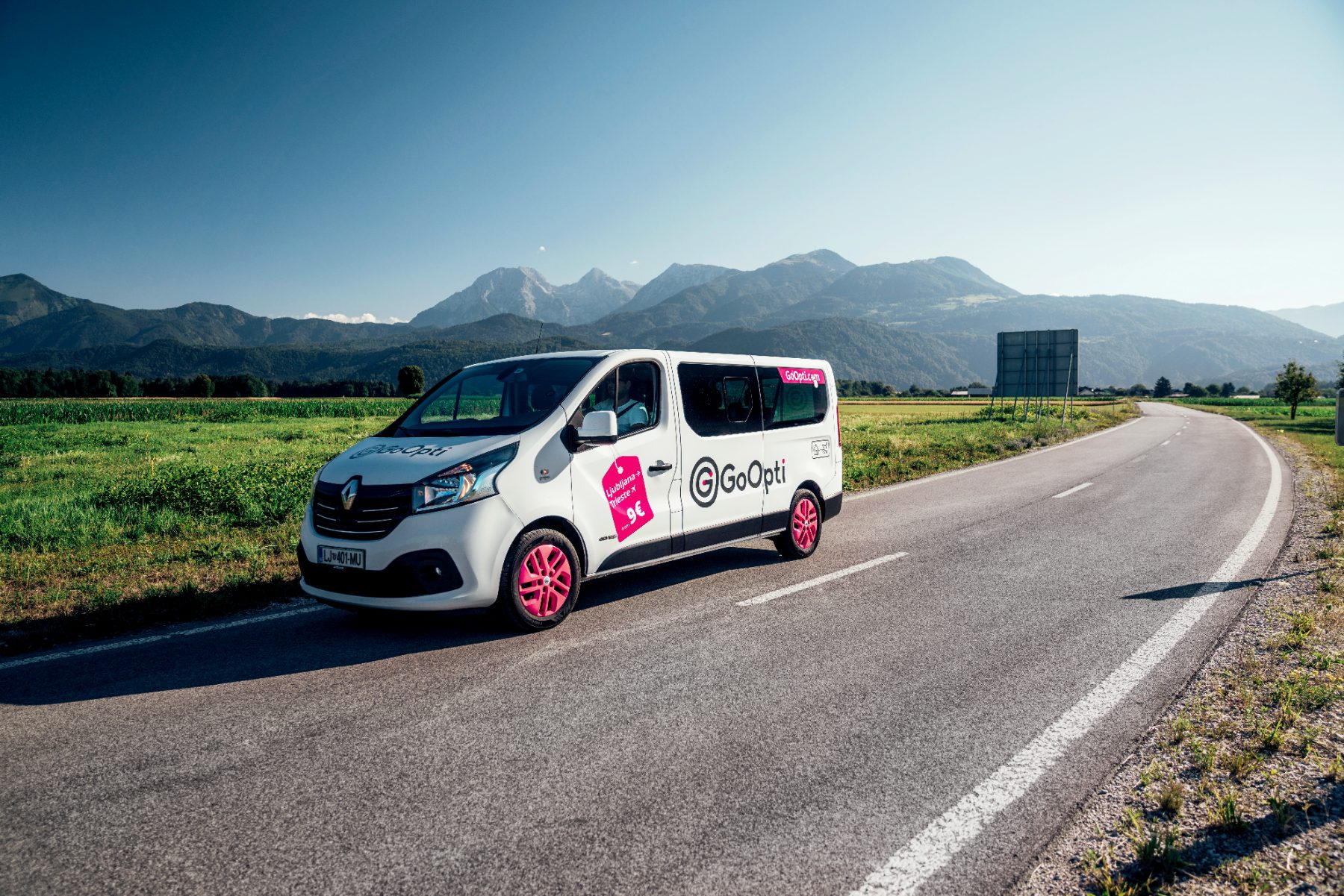 A GoOpti van on the open road with the Slovenian Alps behind